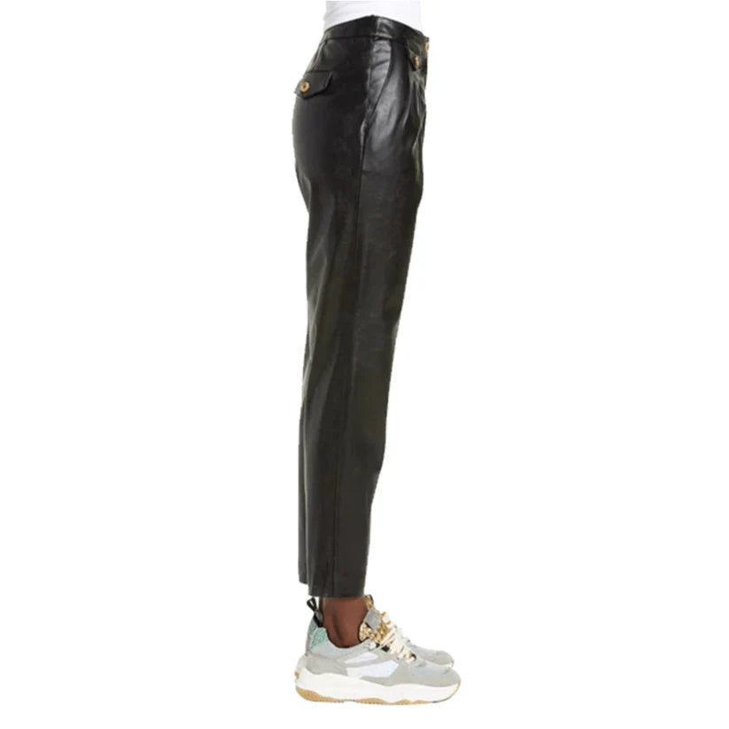 Black leather pants worn with white sneakers on a white background